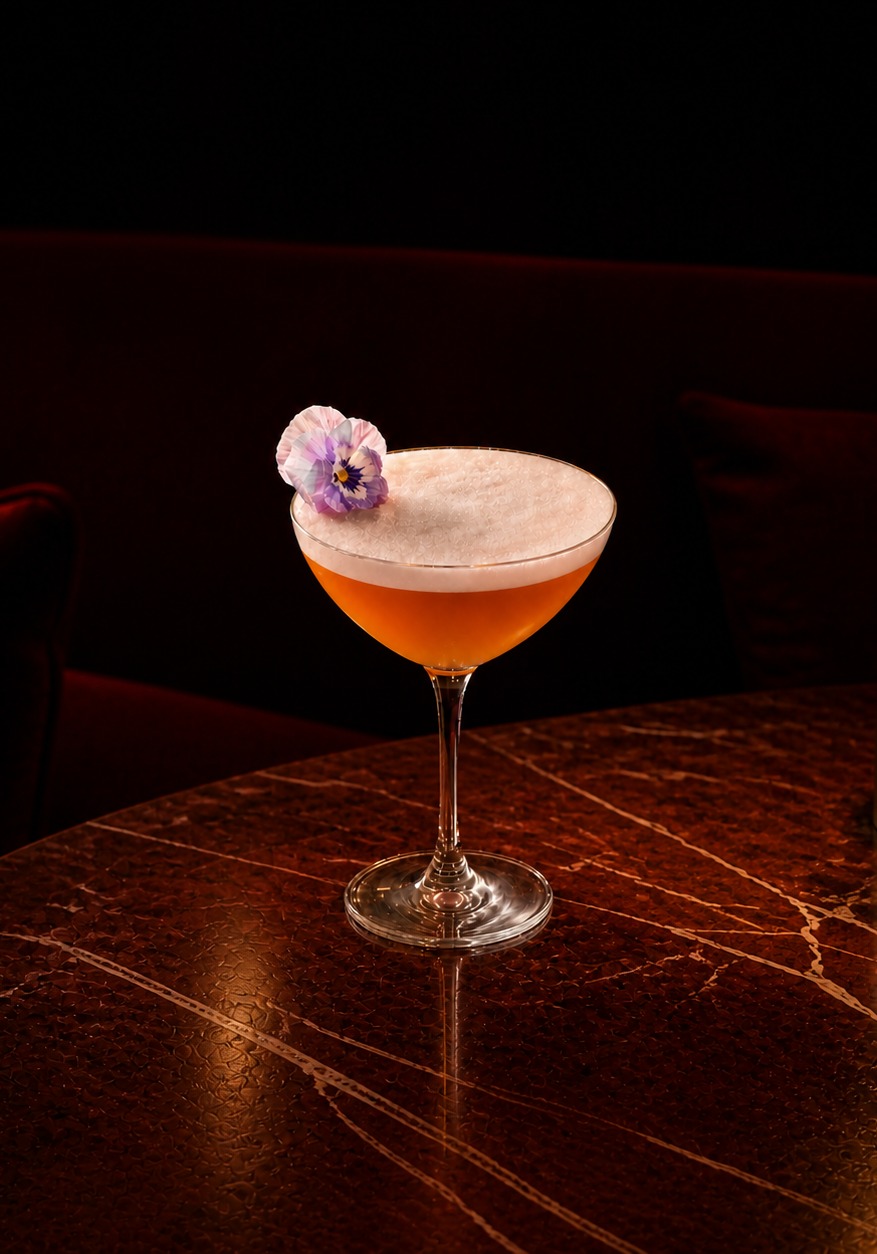 Pale citrus cocktail on the rocks with a sesame-topped spoon